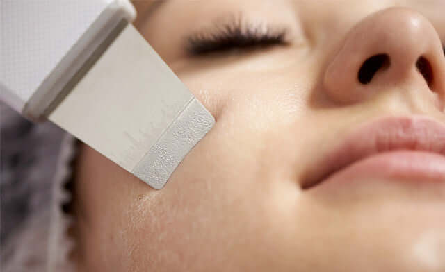 Close-up of a woman receiving a facial treatment with a spatula device for skin care, showcasing carelika products.