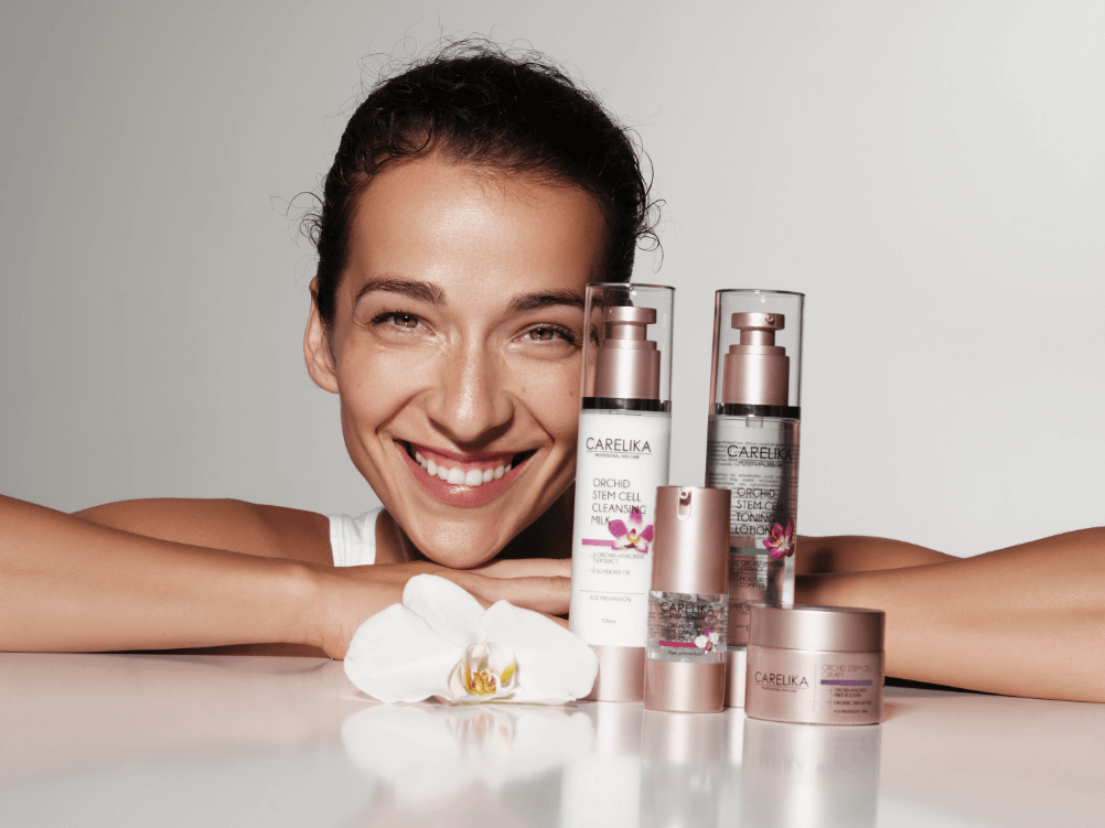 Smiling woman with Carelika skincare products, promoting beauty and self-care.